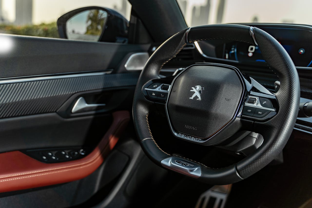 Close-up of a luxury car interior showcasing a Peugeot steering wheel and dashboard.