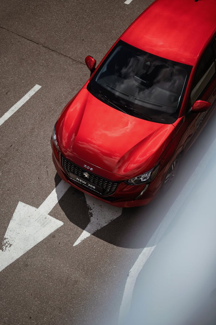 A striking top view of a red car driving on an urban street with road markings.