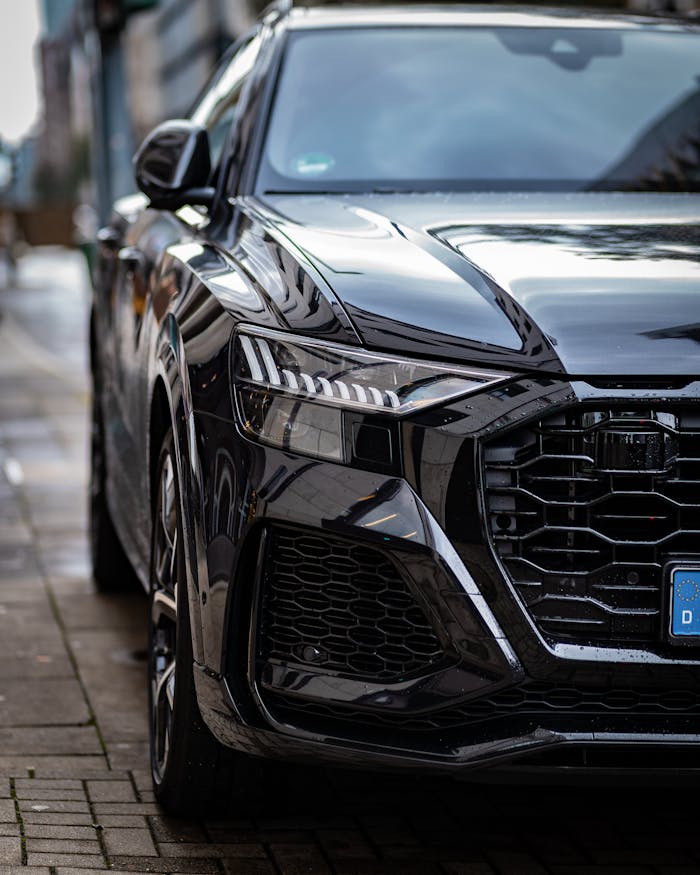 Front view of a sleek black luxury car parked in an urban setting.